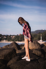 Fototapeta na wymiar Sexy Girl in flannel shirt on the rocky beach.
