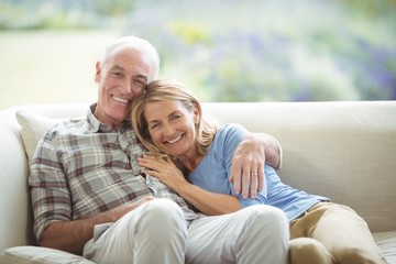 Smiling senior couple sitting together on sofa in living room