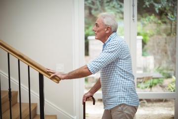 Senior man climbing upstairs with walking stick