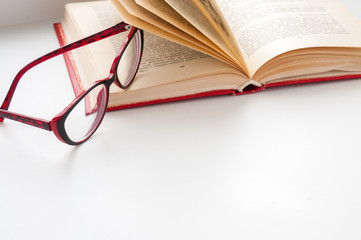 On the open book glasses lie on a light background