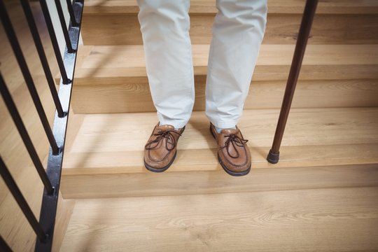 Senior man climbing downstairs with walking stick