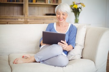 Senior woman using digital tablet in living room