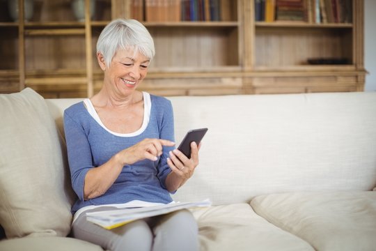 Senior woman using mobile phone in living room