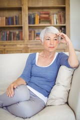 Obraz premium Thoughtful senior woman sitting on sofa in living room