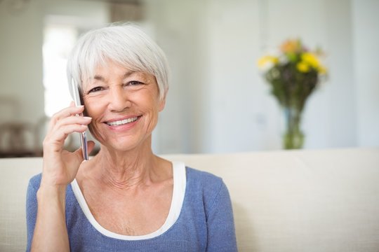 Smiling senior woman talking on mobile phone in living room