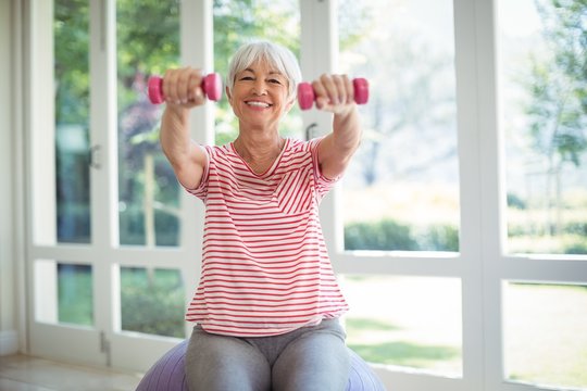 Senior woman exercising with dumbbells at home