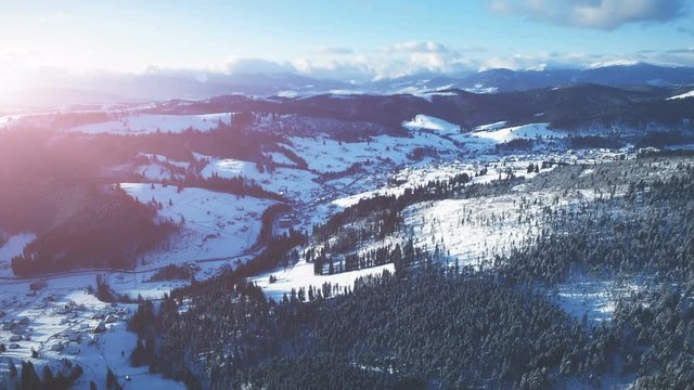 4K Aerial Drone View: Flight over Ski resort in winter. Bright colorful sunset. Mountain range with pine tree forest around. Majestic nature landscape. Bukovel, Carpathian Mountains, Ukraine