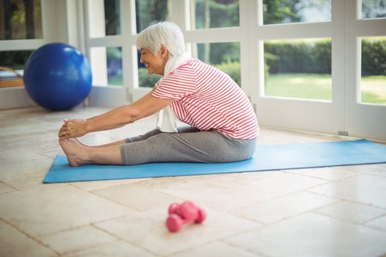 Senior woman performing stretching exercise at home