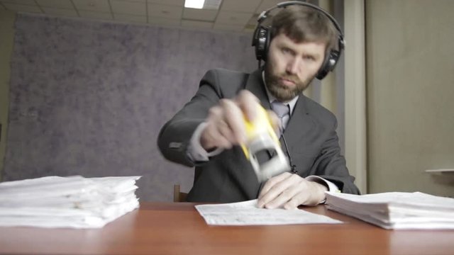 Businessman in headphones funy signing and stamping incoming documents.
