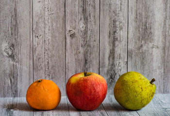 Still life of fruit. Delicious apple, orange and pear lie on a wooden table