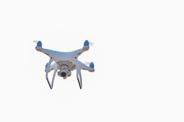 White drone, quadrocopter, with photo camera flying in the blue sky. Drone fly in the blue sky
