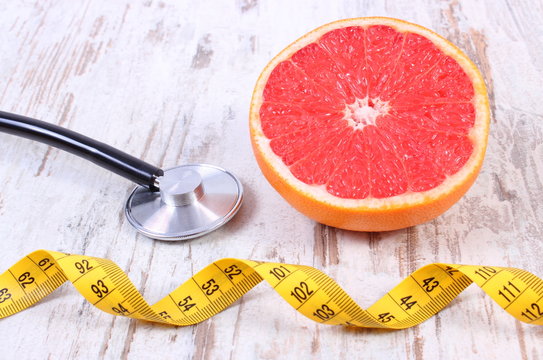 Fresh grapefruit, centimeter and stethoscope on old wooden background