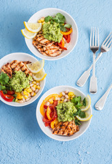 Grilled chicken fajitas bowls on a blue background, top view. Flat lay
