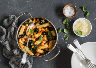 Vegetarian pasta with chickpeas, spinach and tomato sauce. On a gray background, top view