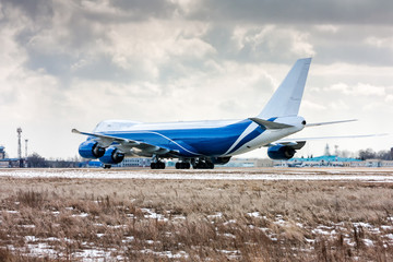 Big cargo aircraft moves on the runway at a cold winter airport