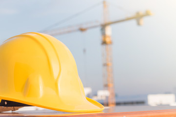 The yellow safety helmet on the table at construction site with crane background
