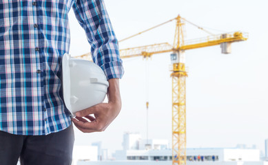 The engineer holding the white helmet safety at construction site with crane background