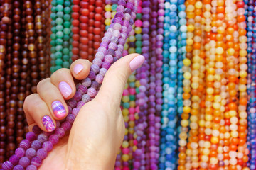 Woman hand with background of multicolored beads made of natural stone