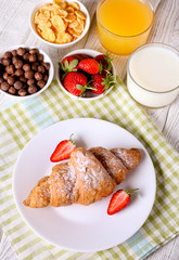 Breakfast with croissants, milk, orange juice and cornflakes