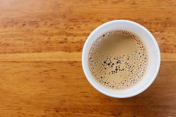 Top view of paper cup of black coffee on wooden table