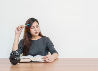 Closeup asian woman sitting for read a book with thinking face emotion on wood table and white cement wall textured background with copy space