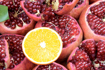 Sliced orange on background of sliced pomegranates