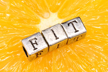 Word of metal letters FIT on citrus orange fruit - health concept