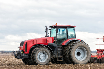 Farmer tractor working in the field. Spring time for sowing. Planting crops.