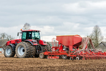 Obraz premium Farmer tractor working in the field. Spring time for sowing. Planting crops.