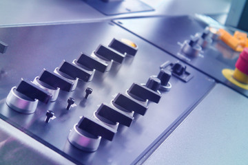 Control panel with buttons and levers and blurred red button
