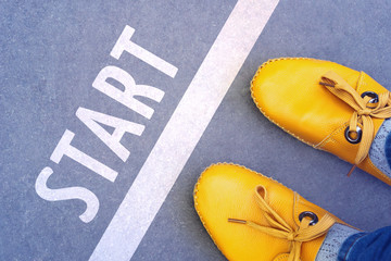 Feet in the yellow shoes standing on start line - business concept