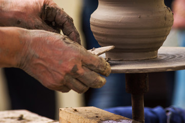 Potter makes pottery on a potter's wheel outdoor close up
