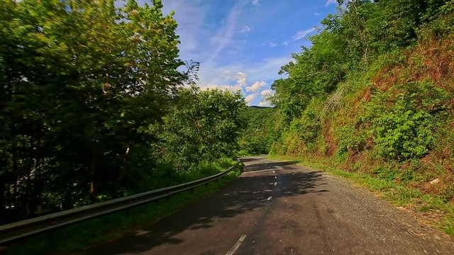 Camera Follows Scooter along Country Road among Hilly Landscape