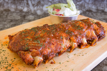 Grilled rib pork with barbecue sauce and vegetable on wooden cutting board.