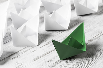 Business leadership concept with white and color paper boats on 