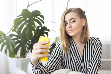 Portrait of beautiful woman taking a self-portrait with her smartphone at home.