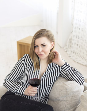 Portrait of happy smiling young attractive woman with glass of red wine, at home