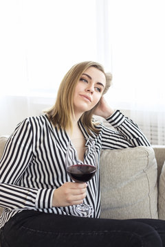 Attractive woman rests at home herself after a hard working day. In her hands holds a large glass of red wine