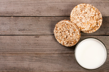 glass of milk with grain crispbreads on old wooden background with copy space for your text. Top view
