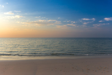 Naklejka na ściany i meble Empty white sandy beach and clear sea at early sunset.