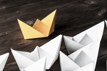 Business leadership concept with white and color paper boats on 