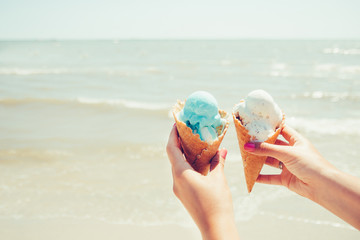 Woman's hands is holding two ice cream on sea background. Summer. Vacation
