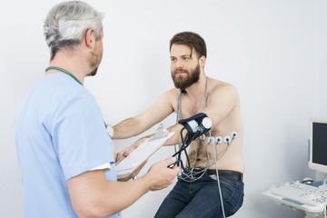 Doctor Checking Blood Pressure Of Patient On Exercise Bike