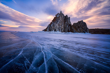 Lake Baikal during warm sunrise in winter. Beautiful rocks and crack lines on ice.