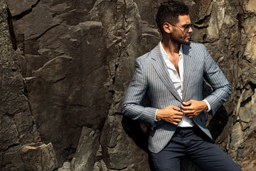 Man in elegant suite posing in rock background