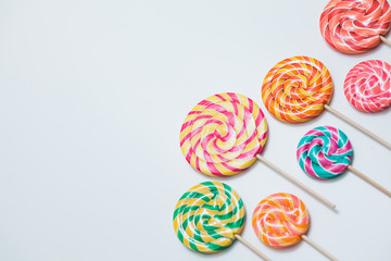 Colorful lollipops on sticks on white table. Sweet caramel candy. Copy space