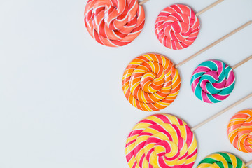 Fototapeta na wymiar Colorful lollipops on sticks on white table. Sweet caramel candy. Copy space