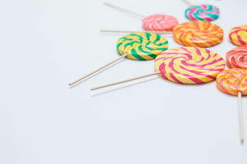 Yummy lollipops on sticks on white table. Sweet caramel candy. Copy space