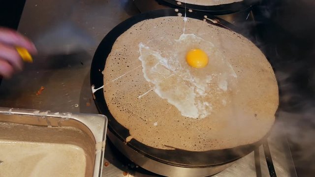 4K close up of a crepe heating with an egg on top. A crepe, or buckwheat pancake, in his cr&ecirc;perie restaurant, in Brittany. Galette bretonne, creperie, Rennes, Bretagne, France. French traditional food