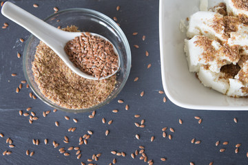 Homemade cottage cheese cream with crushed flax seeds on stone background